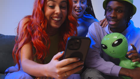 Close-Up-Studio-Shot-Of-Young-Gen-Z-Friends-Sitting-On-Sofa-Sharing-Social-Media-Post-On-Mobile-Phones-4